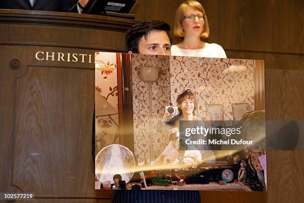 Christie's employee holds a photograph of Jane Birkin during the auction at Christie's for Association Chaine de l'Espoir on July 1, 2010 in Paris,...