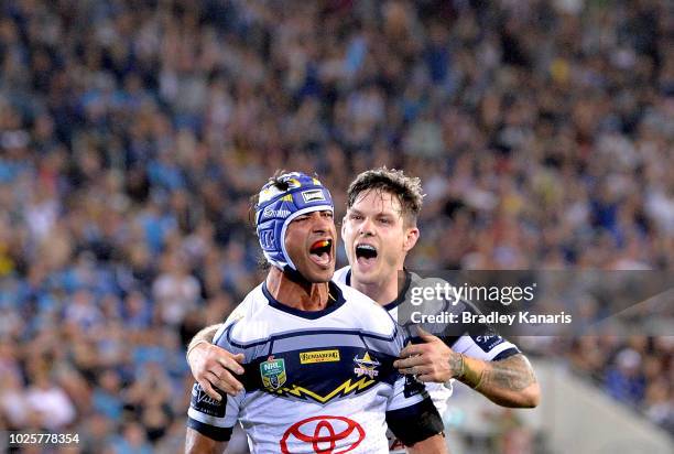Johnathan Thurston of the Cowboys celebrates a try by team mate Gavin Cooper during the round 25 NRL match between the Gold Coast Titans and the...