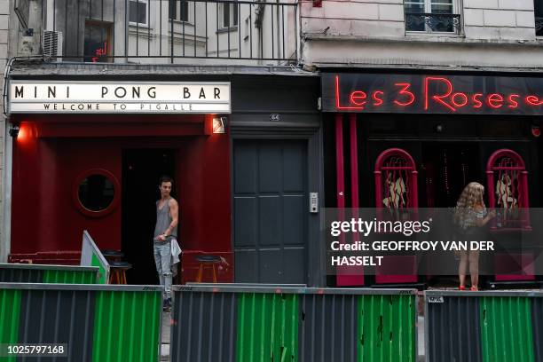 Bartender from the Mini Pong, a former escort-girl bar, and a worker of Les 3 Roses escort-girl bar, stand on the sidewalk in the Pigalle area of...