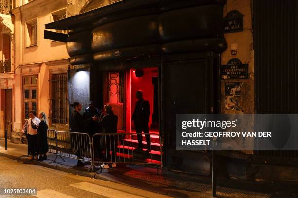 People stand outside a club in Pigalle in the Pigalle area of Paris, on August 31, 2018. - In the southern section of Paris' Pigalle red light...