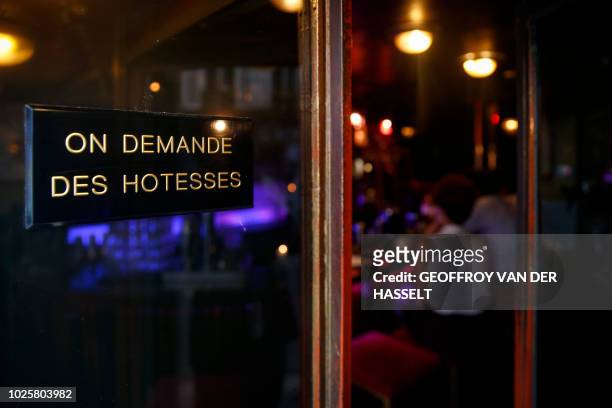An old sign reading "We are looking for hostesses" is displayed at the entrance of the Pile ou Face bar, formerly an escort-girl bar, in the Pigalle...