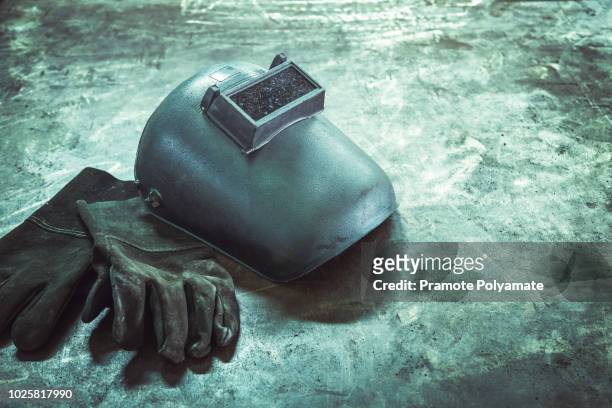 inverted welding machine welding equipment on a wooden desk with welding mask, leather gloves, accessories for arc welding. - red glove stock pictures, royalty-free photos & images