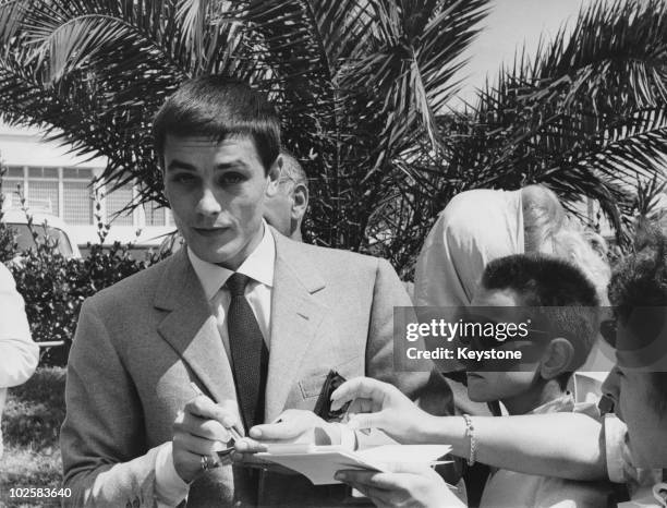 French actor Alain Delon signs autographs for young fans in Cannes during the film festival, 11th May 1961.
