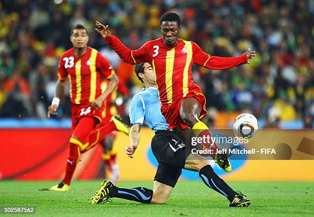 Asamoah Gyan of Ghana is tackled by Andres Scotti of Uruguay during the 2010 FIFA World Cup South Africa Quarter Final match between Uruguay and...