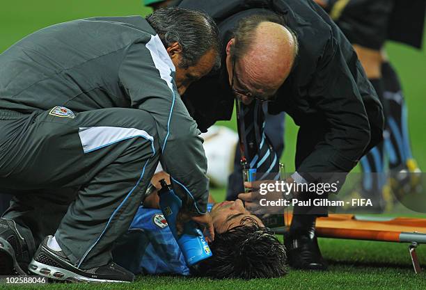 Jorge Fucile of Uruguay receives medical treatment after falling awkwardly during the 2010 FIFA World Cup South Africa Quarter Final match between...