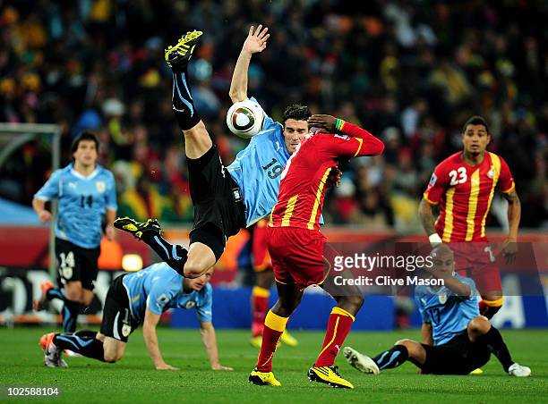 Andres Scotti of Uruguay challenges for a high ball above Asamoah Gyan of Ghana during the 2010 FIFA World Cup South Africa Quarter Final match...
