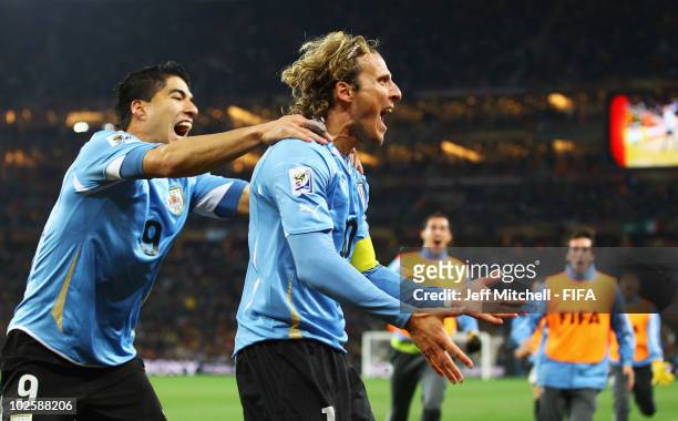 Diego Forlan of Uruguay celebrates scoring his side's first goal from a free kick with team mate Luis Suarez during the 2010 FIFA World Cup South...