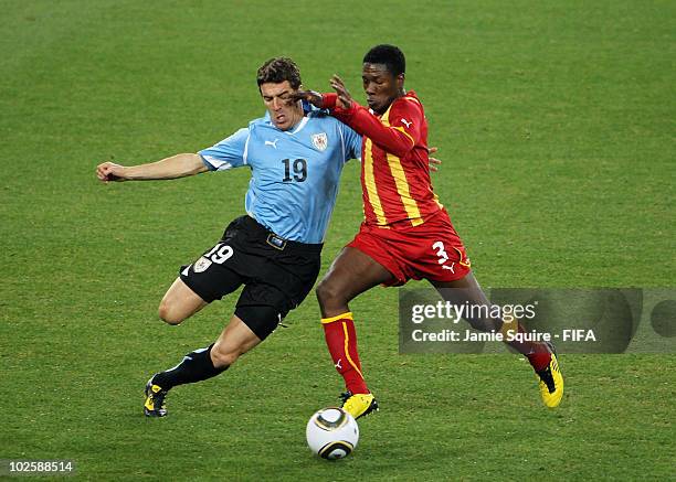 Andres Scotti of Uruguay tackles Asamoah Gyan of Ghana during the 2010 FIFA World Cup South Africa Quarter Final match between Uruguay and Ghana at...