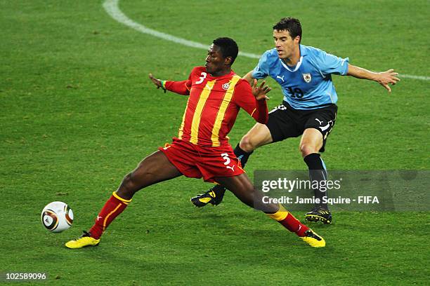 Asamoah Gyan of Ghana attempts to control the ball as he is closed down by Andres Scotti of Uruguay during the 2010 FIFA World Cup South Africa...