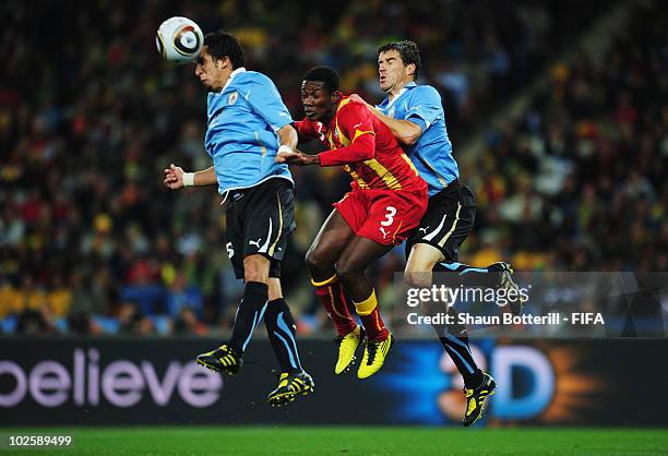 Asamoah Gyan of Ghana jumps between Mauricio Victorino and Andres Scotti of Uruguay during the 2010 FIFA World Cup South Africa Quarter Final match...