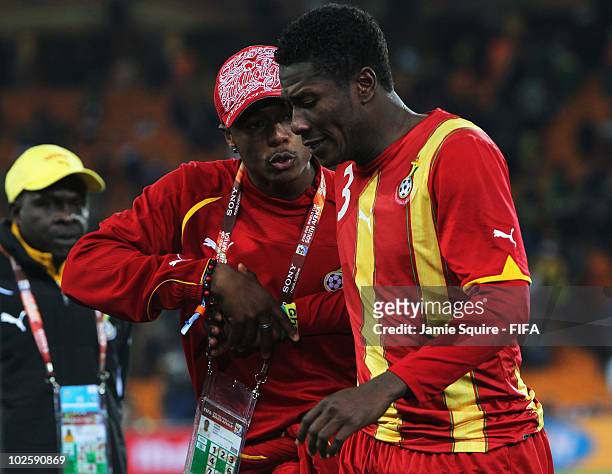 Member of the coaching staff tries to console Asamoah Gyan of Ghana after they lose the penalty shoot out and are out of the tournament during the...