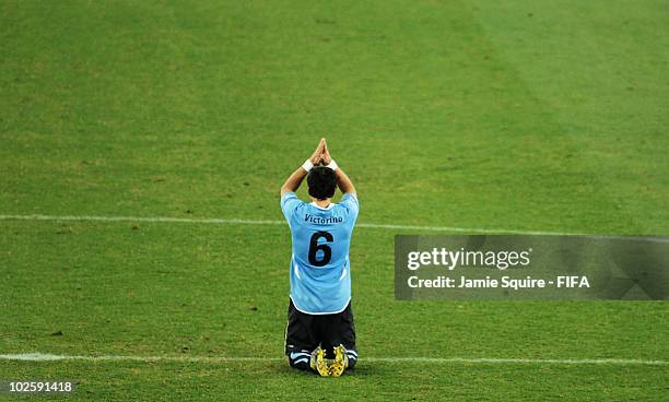 Mauricio Victorino of Uruguay kneels and prays after his team wins the penalty shoot out and progress to the semi finals during the 2010 FIFA World...