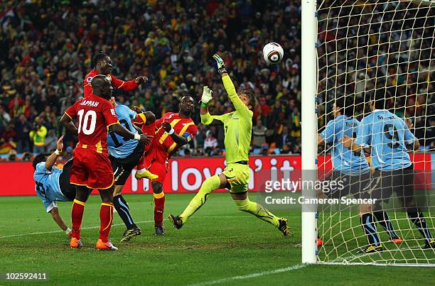 Dominic Adiyiah of Ghana heads on target as Luis Suarez of Uruguay handles the ball on the goal line, for which he is sent off, during the 2010 FIFA...
