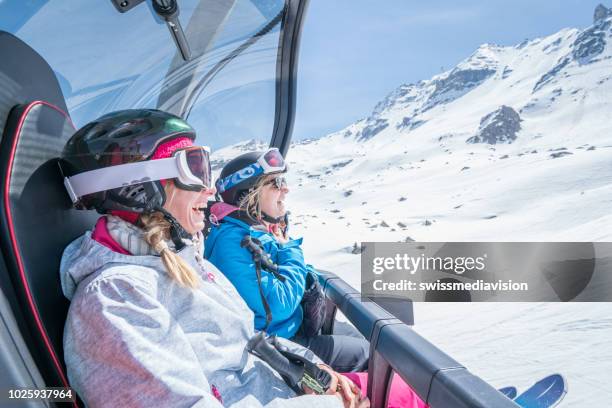 two young women on ski lift in switzerland, ski holidays of two girls tourist enjoying swiss alps and vacations concept - cable car stock pictures, royalty-free photos & images