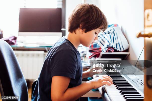 boy playing the piano (nine years old) in a domestic room - electric piano stock pictures, royalty-free photos & images