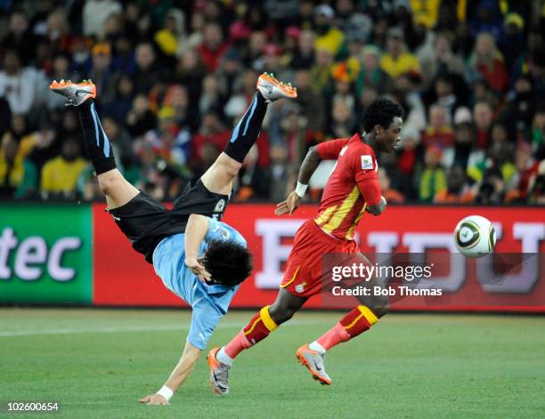 Jorge Fucile of Uruguay falls following a high challenge with Samuel Inkoom of Ghana during the 2010 FIFA World Cup South Africa Quarter Final match...