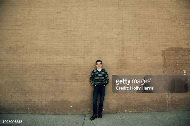young man standing against brick wall, hands in pockets, full body, smiling, striped sweater - fargo north dakota stock pictures, royalty-free photos & images