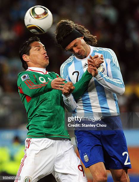 Guillermo Franco of Mexico and Martin Demichelis of Argentina jump for the ball during the 2010 FIFA World Cup South Africa Round of Sixteen match...