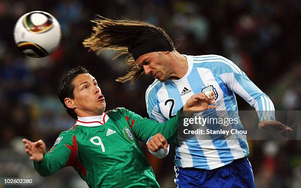 Guillermo Franco of Mexico and Martin Demichelis of Argentina jump for the ball during the 2010 FIFA World Cup South Africa Round of Sixteen match...