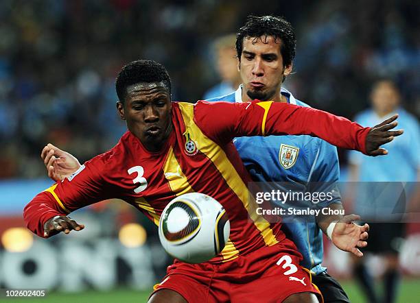Jorge Fucile of Uruguay watches Asamoah Gyan of Ghana during the 2010 FIFA World Cup South Africa Quarter Final match between Uruguay and Ghana at...
