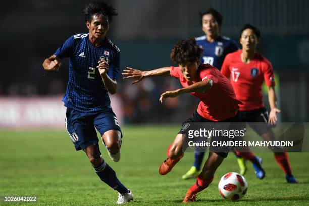 South Korea's Kim Jinya fights for the ball with Japan's Yoichi Naganuma during the men's football gold medal match between Japan and South Korea at...