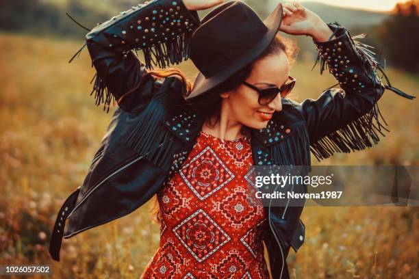 vista traseira do mulher jovem feliz dançando no campo - leather jacket - fotografias e filmes do acervo