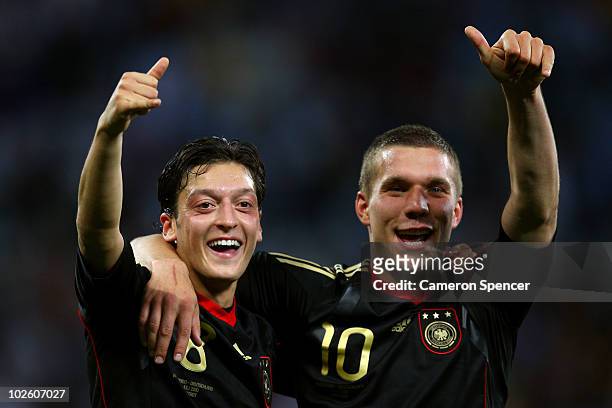 Mesut Oezil and Lukas Podolski of Germany celebrate victory following the 2010 FIFA World Cup South Africa Quarter Final match between Argentina and...