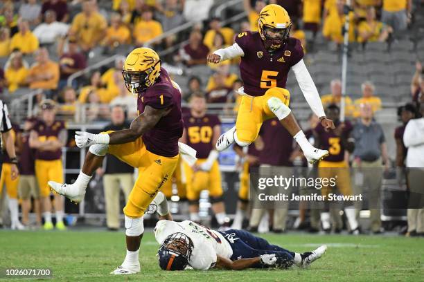 Wide receiver N'Keal Harry and quarterback Manny Wilkins of the Arizona State Sun Devils jump over cornerback Clayton Johnson of the UTSA Roadrunners...