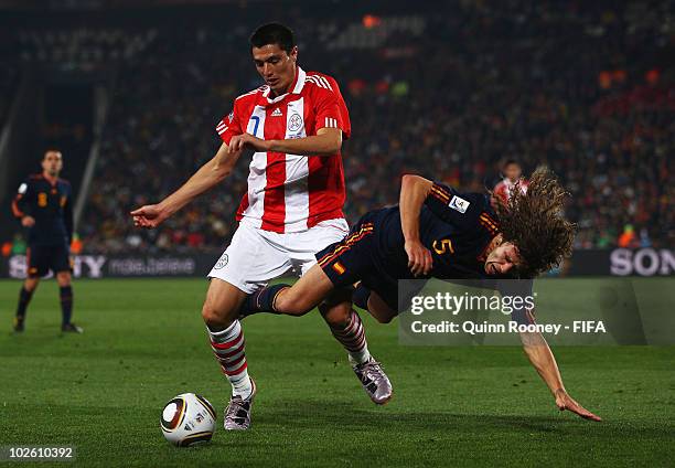 Carles Puyol of Spain tangles with Oscar Cardozo of Paraguay during the 2010 FIFA World Cup South Africa Quarter Final match between Paraguay and...