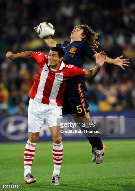 Oscar Cardozo of Paraguay heads the ball with Carles Puyol of Spain during the 2010 FIFA World Cup South Africa Quarter Final match between Paraguay...
