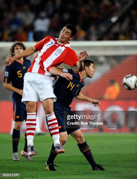 Xabi Alonso of Spain challenged by Oscar Cardozo of Paraguay during the 2010 FIFA World Cup South Africa Quarter Final match between Paraguay and...