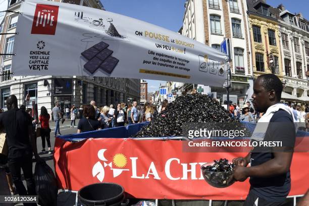 An employee of "La Chicoree" restaurant is about to empty a bucket of empty mussel shells onto a pile during the annual Braderie de Lille on...