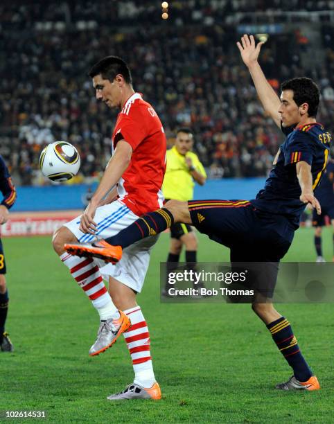 Oscar Cardozo of Paraguay challenged by Sergio Busquets of Spain during the 2010 FIFA World Cup South Africa Quarter Final match between Paraguay and...