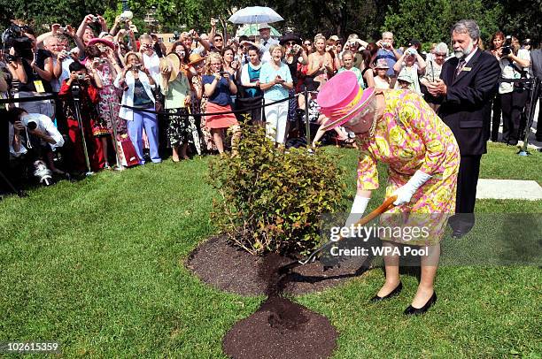 Queen Elizabeth II plants a tree in the garden of Government House, where she also unveiled a statue of herself on July 3, 2010 in Winnipeg, Canada....