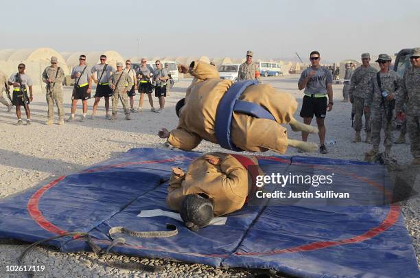 Army Sgt. Richard Hamburg jumps on a friend while sumo wrestling with a friend during an Independence Day BBQ for troops at Kandahar Airfield July 4,...