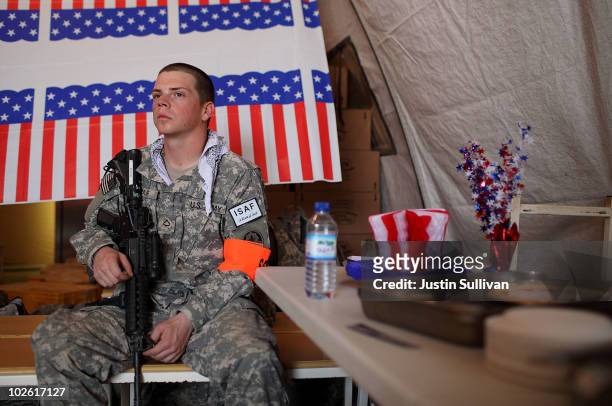 Private First Class Thomas Baur provides security in a tent with tables of desserts during an Independence Day BBQ for troops at Kandahar Airfield...