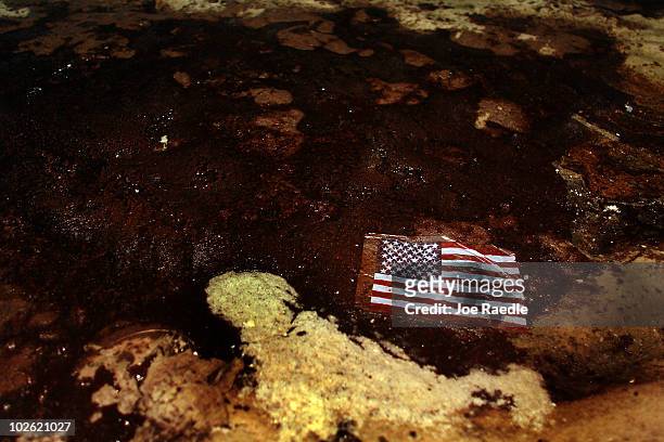 An American flag lays in a slick of oil that washed ashore from the Deepwater Horizon oil spill in the Gulf of Mexico on July 4, 2010 in Gulf Shores,...