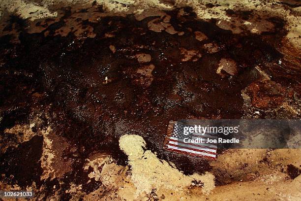 An American flag lays in a slick of oil that washed ashore from the Deepwater Horizon oil spill in the Gulf of Mexico on July 4, 2010 in Gulf Shores,...