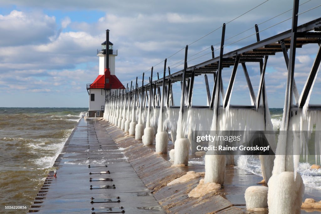 Ice on frozen pier and Lighthouse in winter