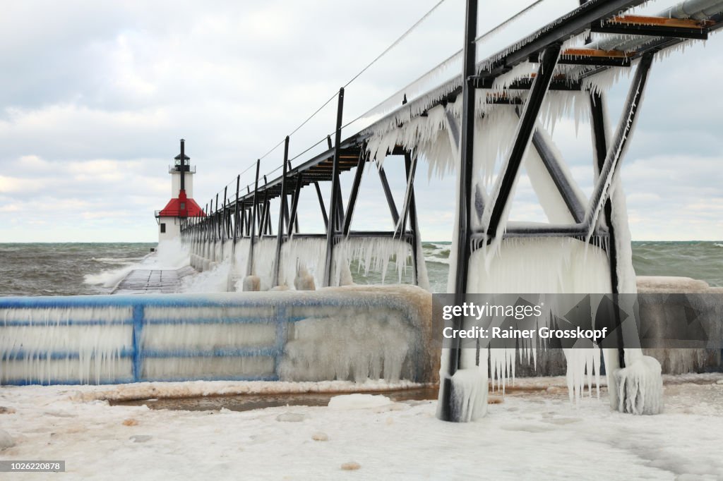 Ice on frozen pier and Lighthouse in winter