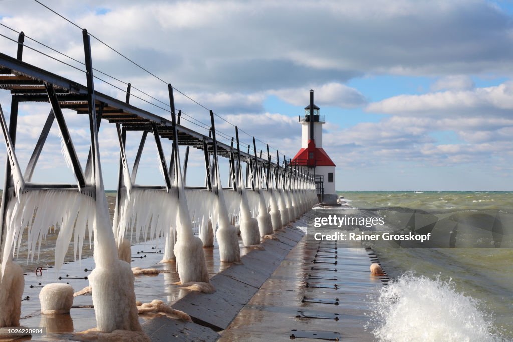 Ice on frozen pier and Lighthouse in winter