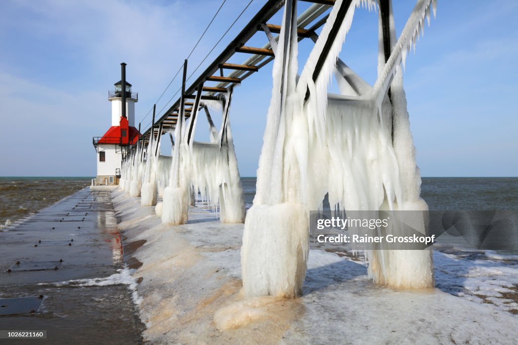 Ice on frozen pier and Lighthouse in winter