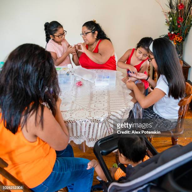 the big happy mexican-american family doing craft, fancy beadworks, together. - alex potemkin or krakozawr latino fitness stock pictures, royalty-free photos & images