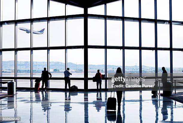 silhouettes of passengers waiting at an airport - terminal aéroportuaire photos et images de collection