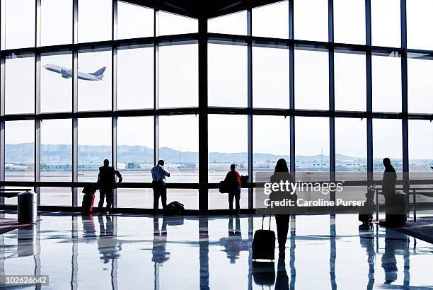 silhouettes of passengers waiting at an airport - airport stockfoto's en -beelden