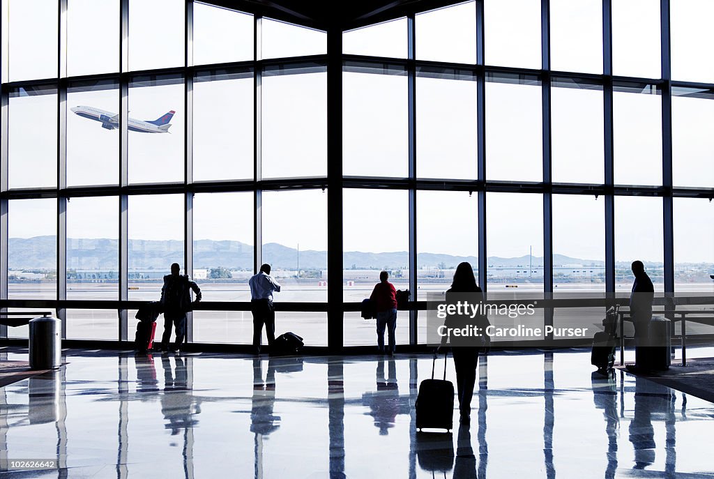 Silhouettes of passengers waiting at an airport