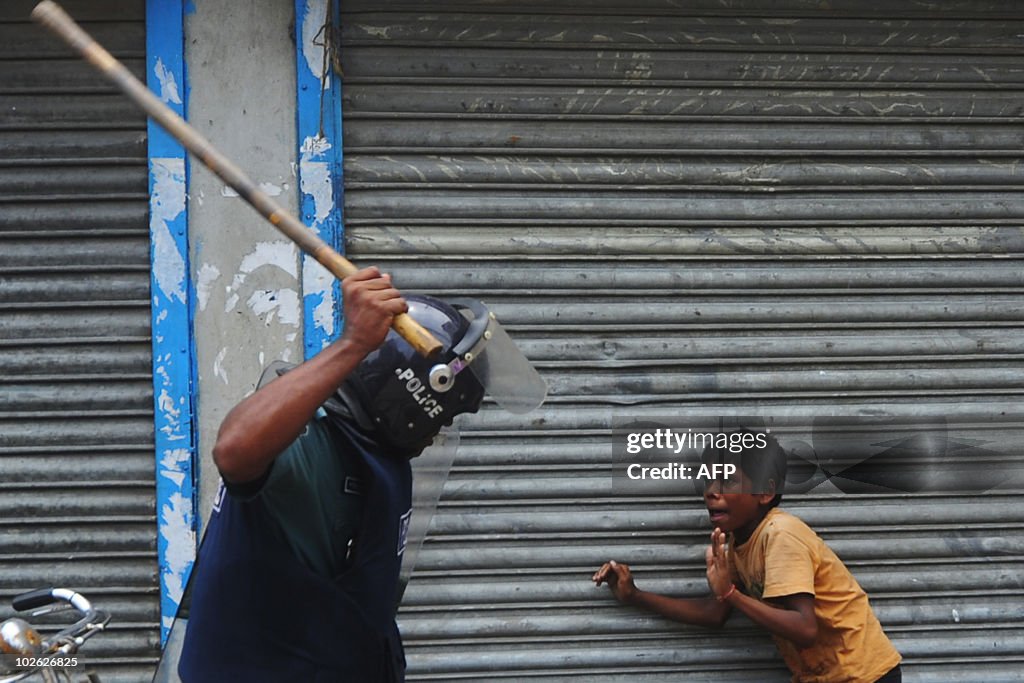 A Bangladeshi policeman threatens a chil