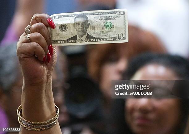 Woman holds up a US dollar bill with a picture of US President Barack Obama as he attends a town hall event on the economy at Racine Memorial Hall in...