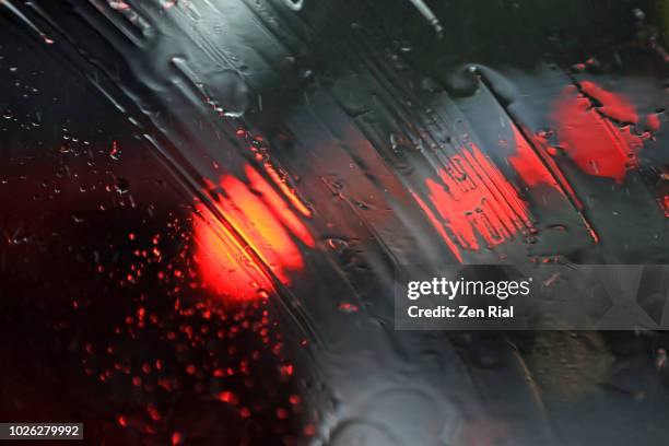 raindrops and traffic lights seen through windshield during heavy rain - phare arrière de véhicule photos et images de collection