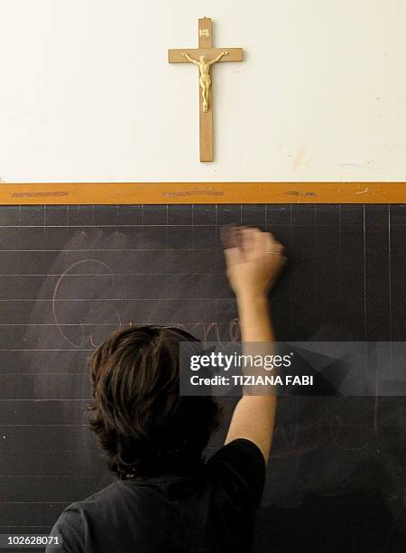 Teacher writes on the blackboard under a crucifix in a classroom in Viterbo on July 1, 2010. Italy began its appeal on June 30, 2010 against a...